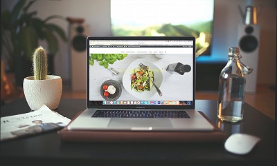 Une table avec un ordinateur posé dessus et ouvert sur la page d'un site internet de restaurant