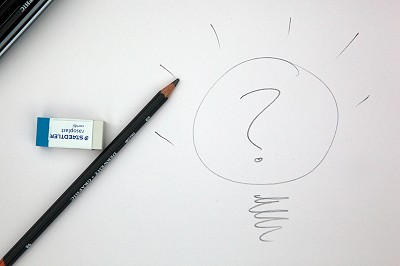 Une gomme et un crayon papier à gauche du dessin d'une lampe avec un point d'interrogation en son milieu